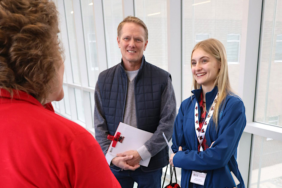 Student & Parent Visit Day Student standing with father speaking to instructor