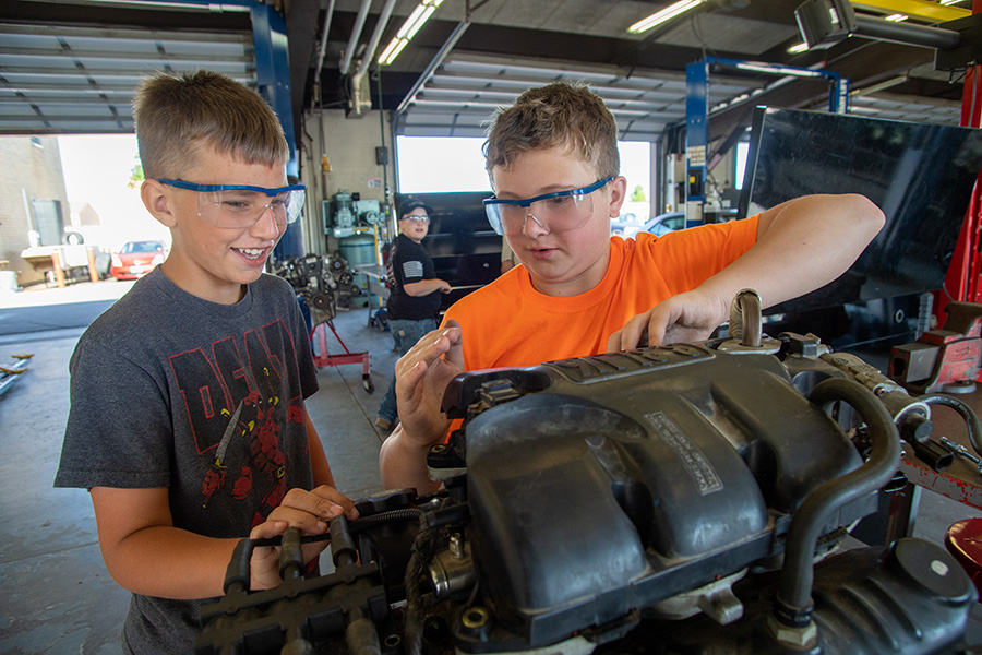 Kidtek students work on a car engine