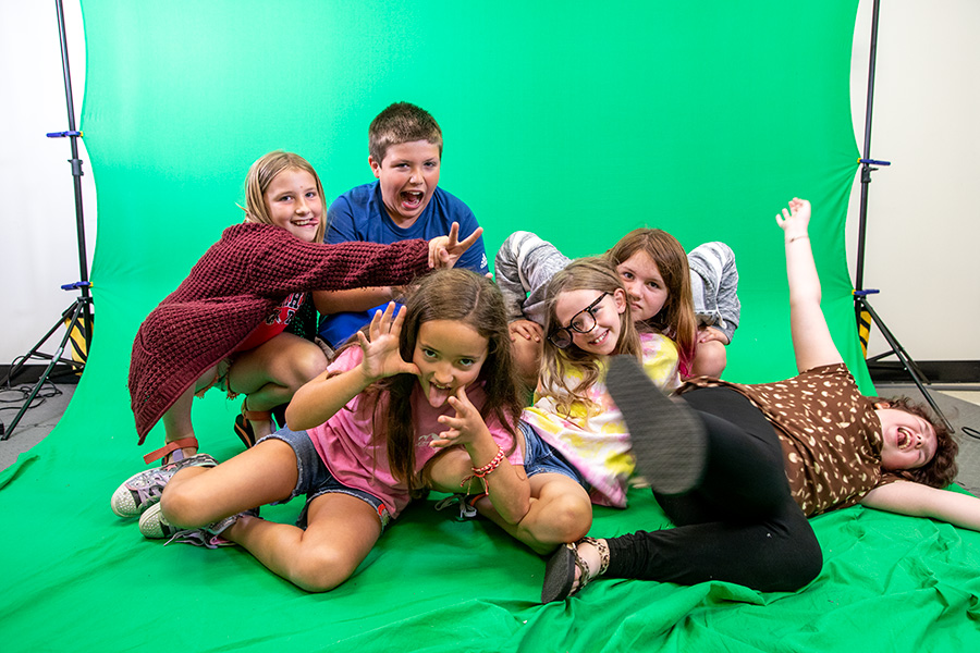 Kidek student ham it up in front of a green screen