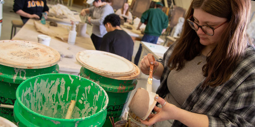 Student glazing a ceramic pot