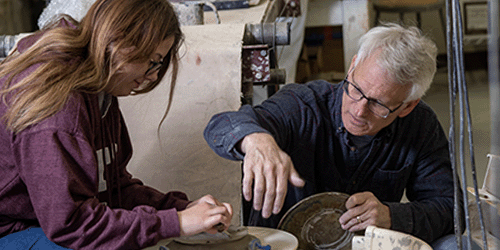 student and professor at a potter's wheel