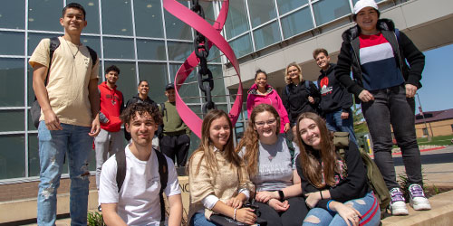 Students posing next to sculpture