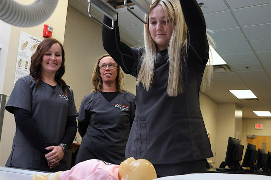 Students using hospital equipment on sim baby.