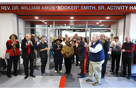 SCC representatives smiling and standing after ribbon cutting at main doors of new activity hall
