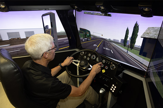 Transportation Instructor Richard Link demos the truck driving simulator.