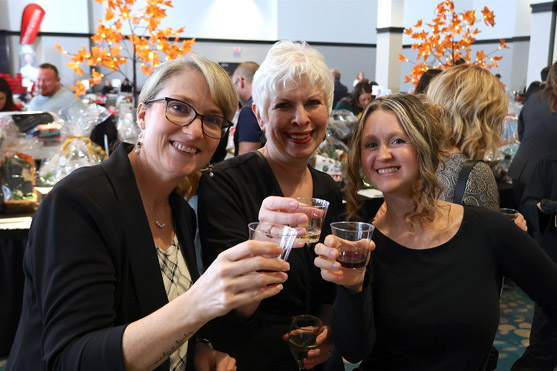 Three women holding glasses smiling