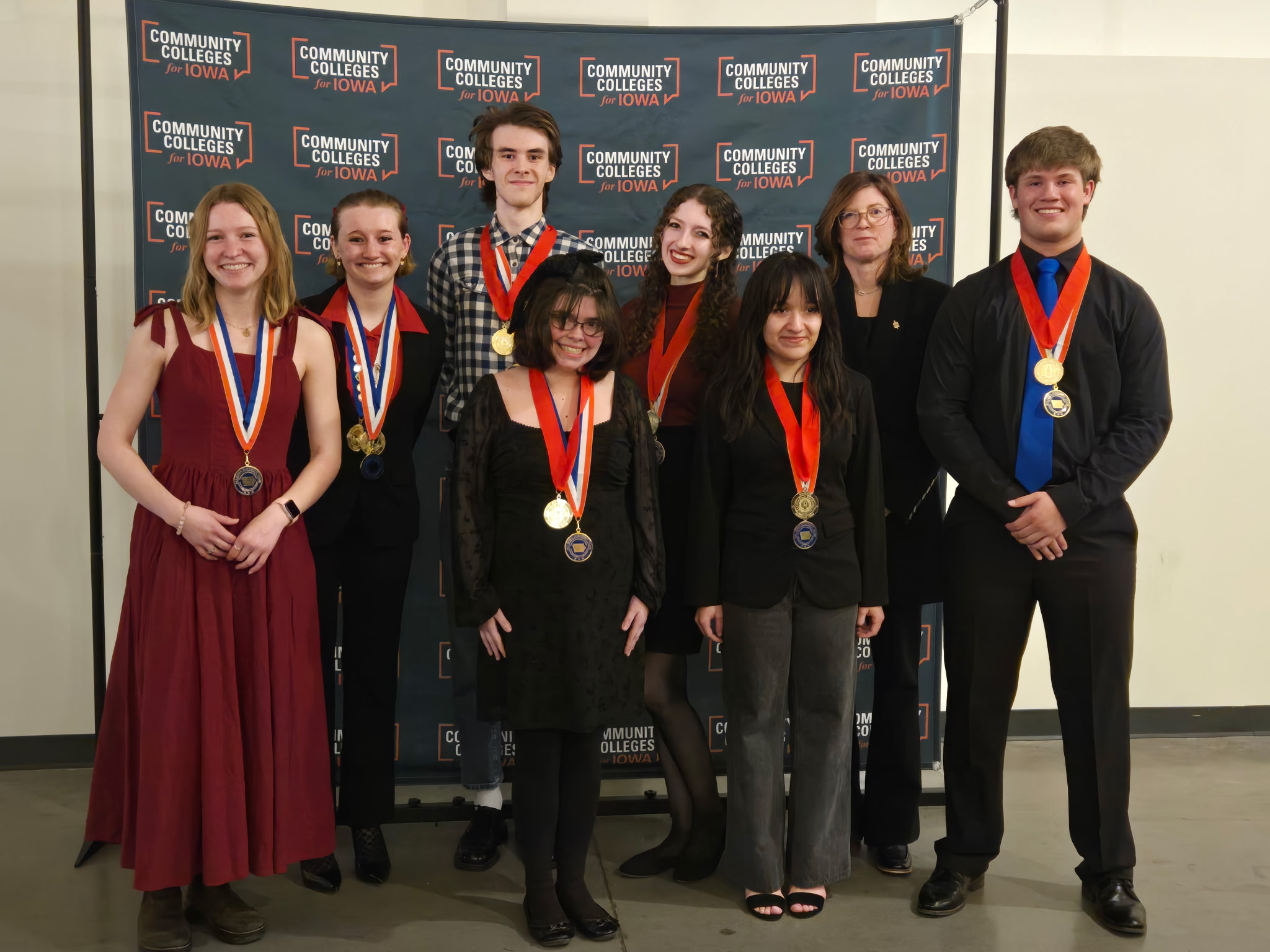 Students posing in front of backdrop with awards