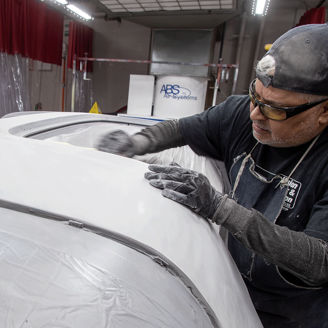 student smoothing out a paint finish on a vehicle